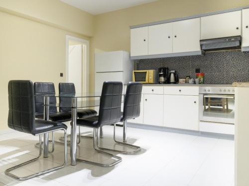 uma cozinha com uma mesa de vidro e cadeiras pretas em Apartment Lazarous 1 em Apolakkiá
