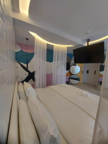 a bedroom with a large white bed with a painting on the wall at ConnectIN Apartments in Pale