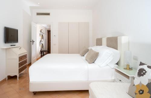 a white bedroom with a white bed and a tv at Hotel Belair in Sorrento