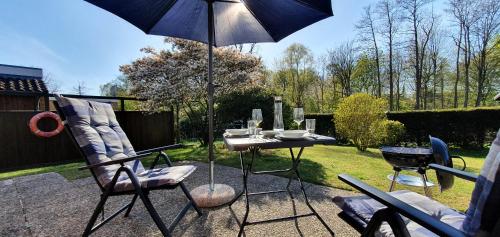 un patio con mesa, sillas y sombrilla en Vogelkoje - Urlaub an der Nordsee in Nordfriesland en Bredstedt