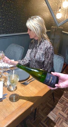 una donna seduta a un tavolo con una bottiglia di vino di The Curious Fox a Skipton