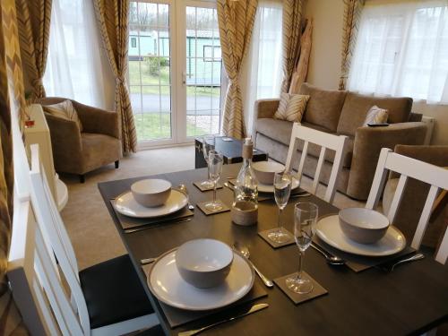a dining room with a table with plates and wine glasses at No1 Borwick Lakes in Carnforth