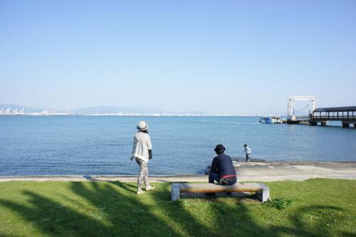Fukuoka - House - Vacation STAY 4674 في فوكوكا: يجلس شخصان على مقعد بجوار الماء
