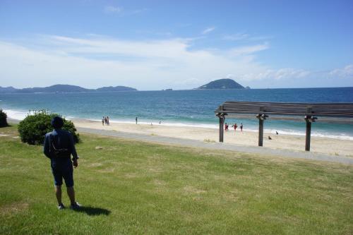 Un homme debout sur l'herbe et regardant la plage dans l'établissement Fukuoka - House - Vacation STAY 4674, à Fukuoka