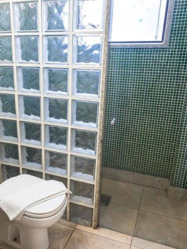 a bathroom with a toilet and a green tiled wall at VOA Plazza Hotel in Águas de Lindóia