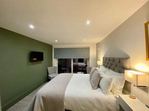 a bedroom with a large white bed with a green wall at Tŷ Treflan in Aberdyfi