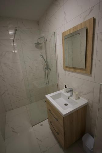 a bathroom with a sink and a shower with a mirror at Apartmani JURIĆ in Međugorje