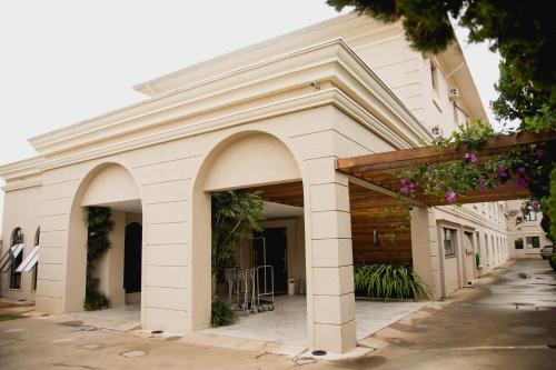 a white building with arches and plants on it at Class Hotel Guaxupé in Guaxupé