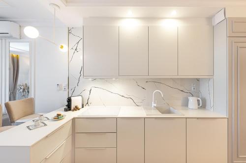 a white kitchen with white cabinets and a sink at Gold Apartment Szczecinek in Szczecinek