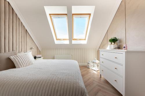 a bedroom with a large white bed with a skylight at Gold Apartment Szczecinek in Szczecinek