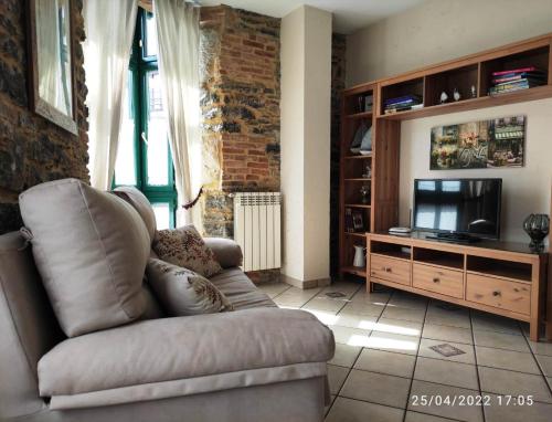 a living room with a couch and a television at Apartamento Campomanes in Villaviciosa