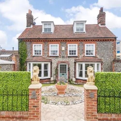a brick house with a fence in front of it at West Cottage. Central, beautiful, 2 mins to beach. in Cromer