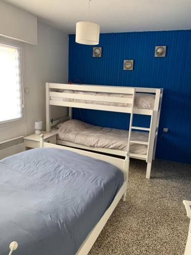 een slaapkamer met 2 stapelbedden en een blauwe muur bij Petite escapade à la Picardière in Fort-Mahon-Plage