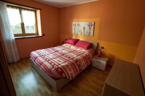 a bedroom with a bed with red sheets and a window at Bernina Apartament in Chiesa in Valmalenco