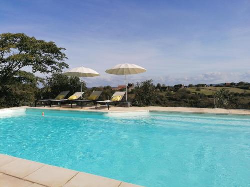 ein Pool mit zwei Sonnenschirmen und einigen Stühlen in der Unterkunft Le Mas de Coline in Rocamadour