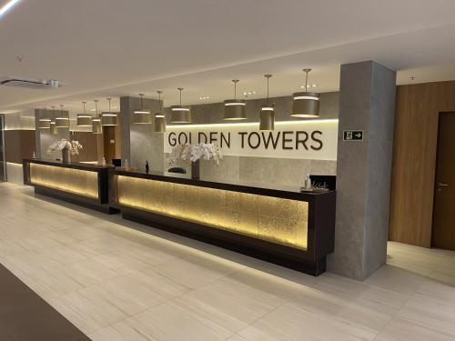 a lobby with a golden towers sign on the wall at Golden Towers Hotel in Macaé