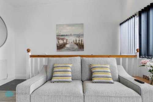 a gray couch with two yellow and white pillows at 4 Bed - Smeatons by Pureserviced in Plymouth