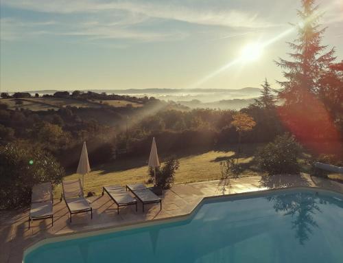 a swimming pool with chairs and a view of a field at Le Mas de Coline in Rocamadour