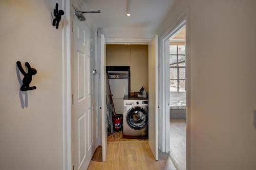 a hallway leading to a kitchen with a washing machine at NEW Grade 2 historic flat in the heart of Chester in Chester