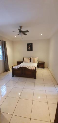 a bedroom with a bed and a ceiling fan at The Rink Apartment's in Sukuta