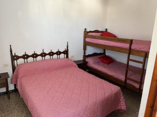 a bedroom with two bunk beds with pink sheets at Apartamento en Peñiscola a 3 minutos andando a la playa con parking in Peniscola