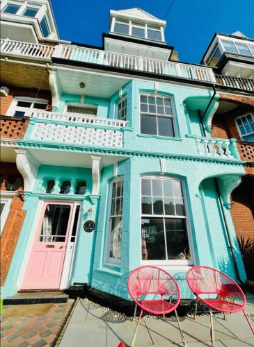 a blue house with two red chairs in front of it at Sea View, Beach Road, Cromer in Cromer