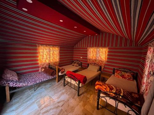een kamer met drie bedden en stoelen in een kamer bij Sunset Dreams camp in Wadi Rum
