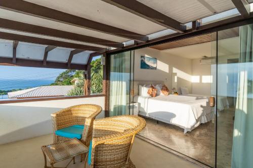a bedroom with a bed and two chairs on a balcony at Eny Boutique Hotel & Spa in Búzios