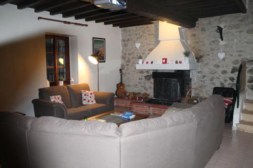 sala de estar con sofá y chimenea en Les Ecuries, traditional stone farmhouse with pool en Marquixanes