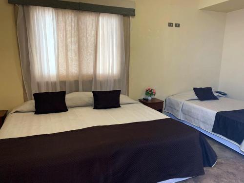 a bedroom with two beds and a window at Juku Hostal in Calama