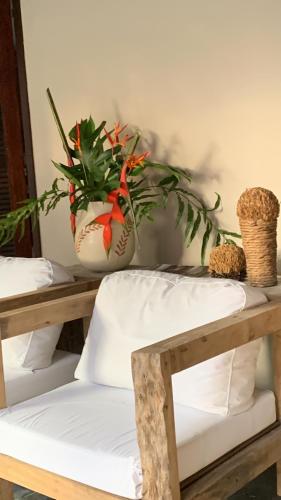 a table with a chair and a vase with flowers at Almas Gêmeas suíte in Angra dos Reis