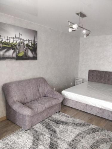 ein Schlafzimmer mit einem Bett, einem Sofa und einem Stuhl in der Unterkunft Studio COMFORT on Golovna street in Czernowitz