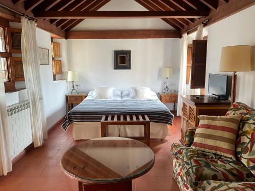 ein Schlafzimmer mit einem Bett, einem Tisch und einem Sofa in der Unterkunft Hotel Santa Isabel La Real in Granada