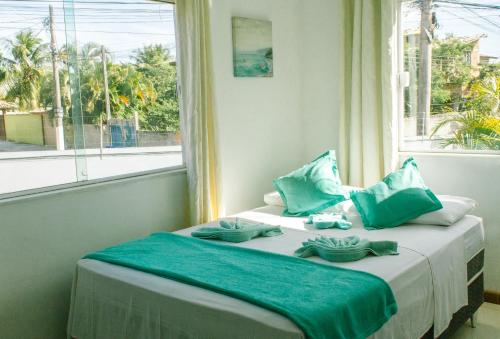 Un dormitorio con una cama con almohadas azules y una ventana en L´Grace Geriba, en Búzios