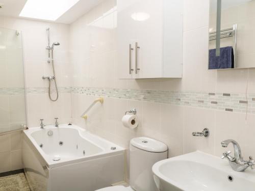 a white bathroom with a tub and a toilet and a sink at Sunnymead Cottage in Halwill