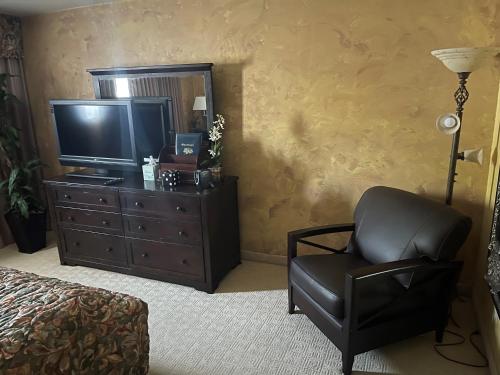 a living room with a chair and a television at Ramada by Wyndham Viscount Suites Tucson East in Tucson