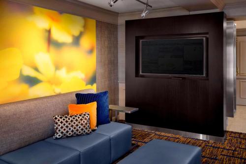 sala de estar con sofá azul y TV en Sonesta Select Boston Danvers, en Danvers