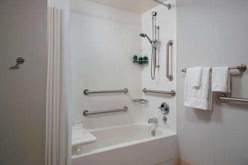 a bathroom with a tub and a shower with towels at Sonesta Select Newport Middletown in Middletown