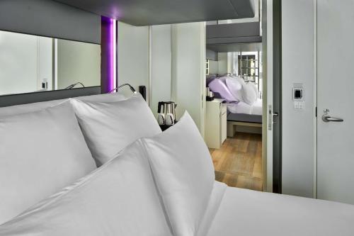 a bedroom with a white bed with a large mirror at YOTEL Singapore Orchard Road in Singapore