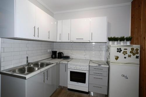 a kitchen with white cabinets and a sink at Bianca Suites in Nea Moudania