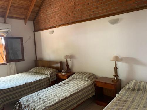 Cette chambre comprend 2 lits et un mur en briques. dans l'établissement Un Lugar Hotel Cabañas, à Eldorado