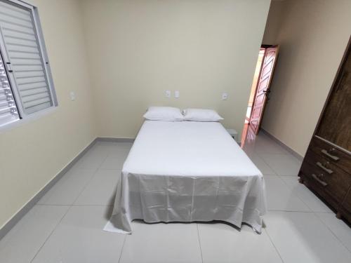 a bedroom with a bed with a white sheet on it at Casa Canastra Bio in São Roque de Minas