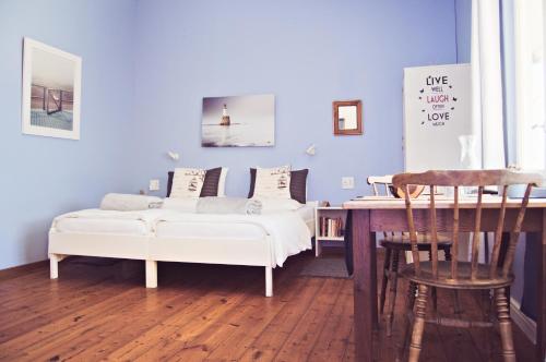 a living room with two white beds and a table at Haus Sandrose in Lüderitz