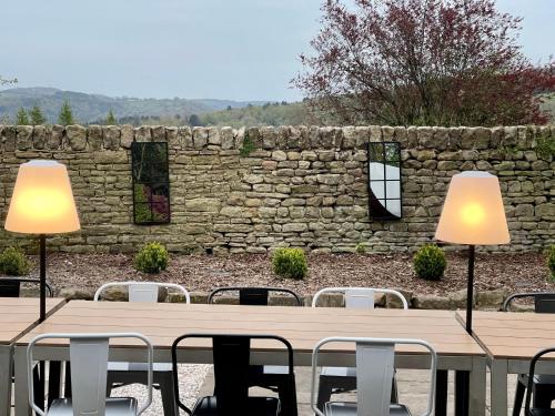 a stone wall with a table and chairs and two lamps at Riber Hall in Matlock Bank