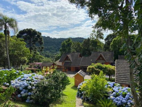 a garden with blue flowers in front of a house at Pousada Maibe Amanhecer na Serra in Gramado