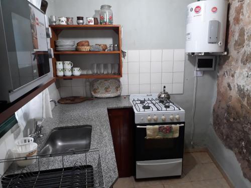 uma pequena cozinha com um fogão e um lavatório em Cabañas La Escondida Casa De Campo 2 em San Antonio de Arredondo