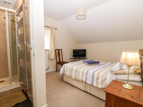 a bedroom with a bed and a desk and a television at Honeysuckle Cottage in Beaworthy