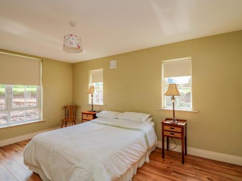 a bedroom with a white bed and two windows at Josie's House in Fethard on Sea