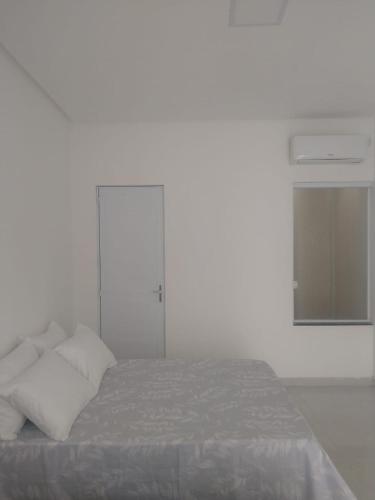 Pousada Parque das Águas في توكانو: غرفة نوم بيضاء بها سرير ونافذة