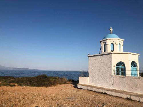 a lighthouse with a cross on top of it next to the ocean at Aegean Touch Beach House in Artemida